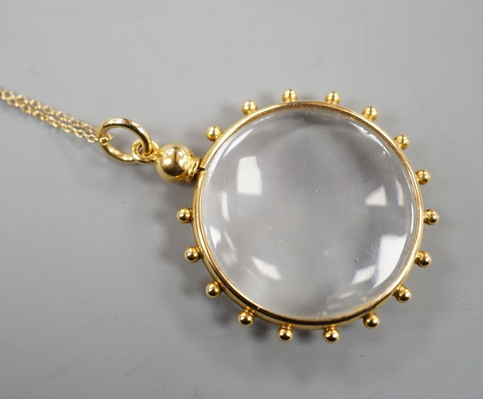 An early 20th century 15ct mounted eye glass pendant, 29mm, on a yellow metal fine link chain, gross 9.3 grams.